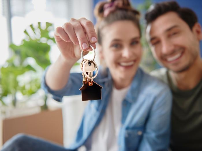Jeune couple souriant tenant une clé avec un porte-clés en forme de maison