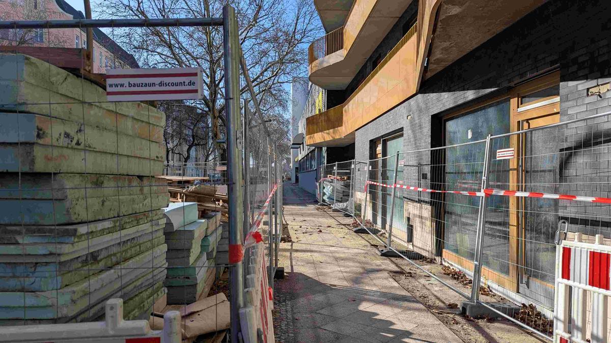 Entrée du chantier de l'immeuble, avec barrières métalliques et matériaux de construction