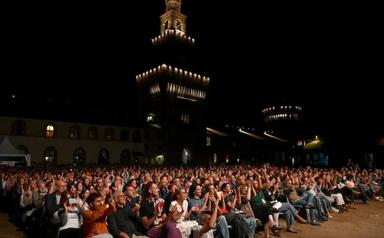 spectateurs assis dans la cour d'un château de nuit