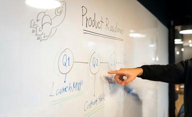 une personne pointe le doigt sur un tableau blanc