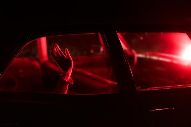 Des mains derrière la vitre d'une voiture avec une lumière rouge.