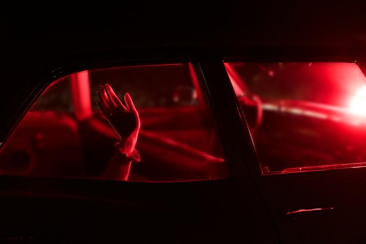 Des mains derrière la vitre d'une voiture avec une lumière rouge.