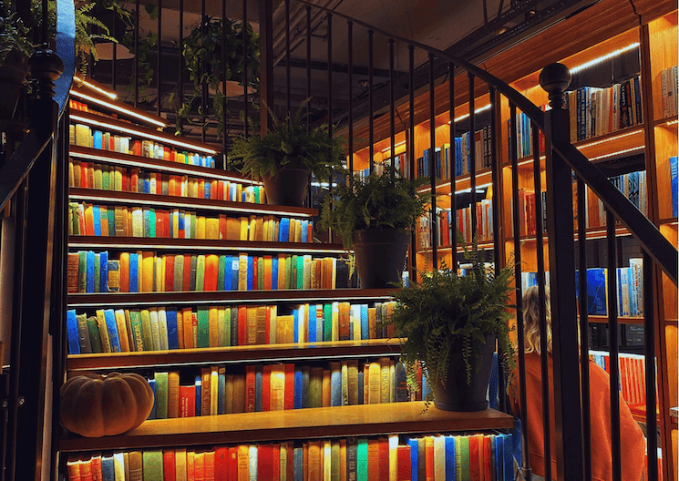 Escalier orné de livres colorés et de plantes au Minoa Pera, café-librairie d’Istanbul classé plus beau book café du monde en 2025.
