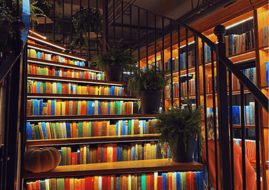 Escalier orné de livres colorés et de plantes au Minoa Pera, café-librairie d’Istanbul classé plus beau book café du monde en 2025.