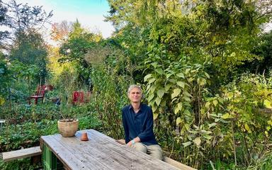 Le propriétaire du Cafe Botanico assis à une table dans le jardin