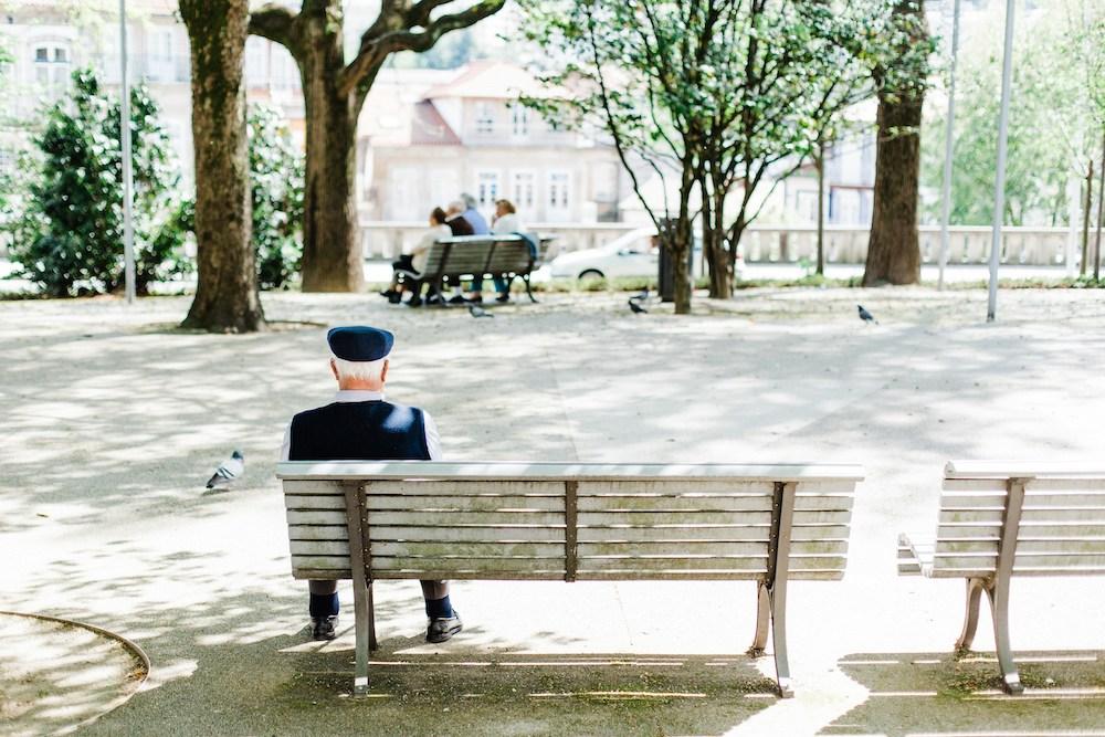 un vieux monsieur est assis sur un banc sur la place du village