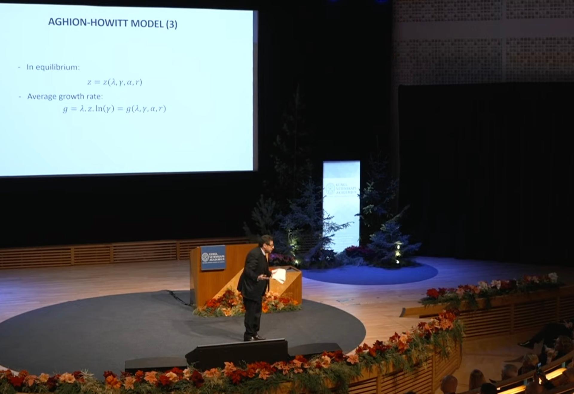 Philippe Aghion, prix nobel 2025 debout sur scène pendant une conférence