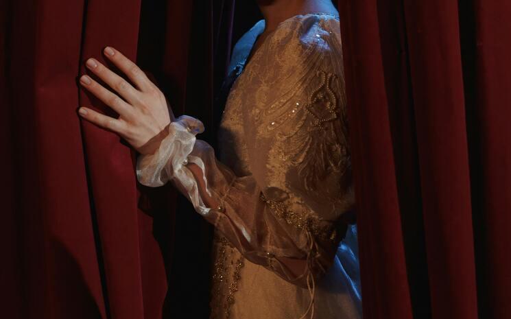 Rideau rouge de théâtre avec un homme qui l'ouvre