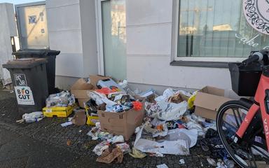 Amas de déchets jetés par terre à côté d'une benne à ordure