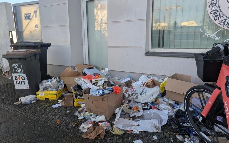 Amas de déchets jetés par terre à côté d'une benne à ordure