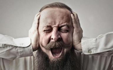 homme en colère qui se bouche les oreilles à cause du bruit