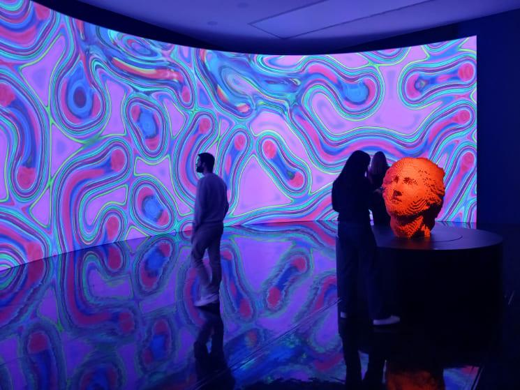 Visiteurs devant une oeuvre numérique colorée