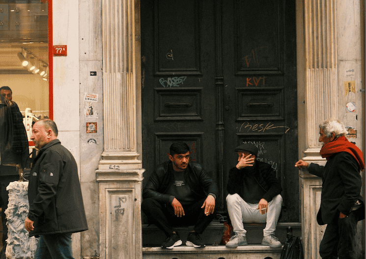 Scène de rue à Istanbul, hommes assis devant une porte, interaction sociale illustrant les nuances relationnelles de la culture turque