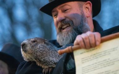 Un homme tient dans ses bras une marmotte et un document.