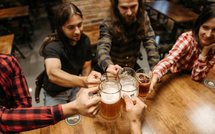 quatre amis autour d'une table qui trinquent avec leurs bières dans un barre