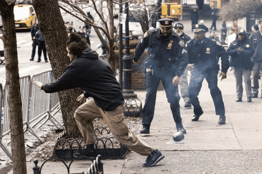 Un homme court et lance un engin explosif lors d'une manifestation à New York, des policiers lui courent après
