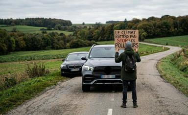 Un activiste faisant face à une Mercedes.