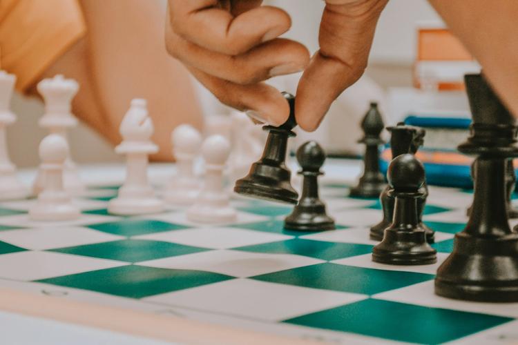 une personne tenant une pièce d’échecs noire et blanche