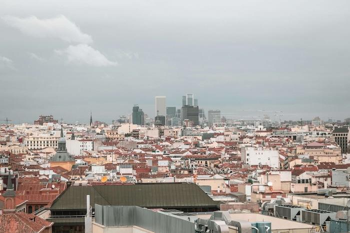 vue d'un espace urbain à madrid avec des toits d'immeubles, des tours au fond dans un ciel gris