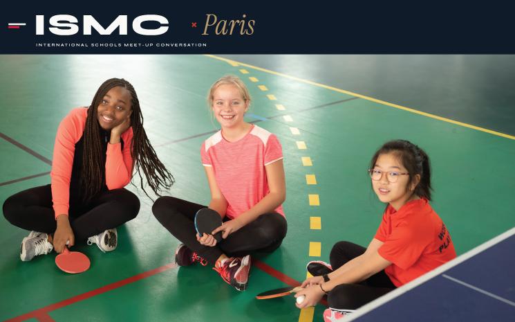 3 enfants accroupis sur un terrain de sport interieur