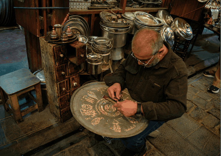artisan réparant un plateau en métal dans un han à Eminönü à Istanbul atelier traditionnel métiers rares Turquie