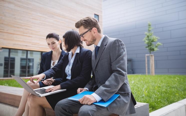businesswoman-sitting-with-colleagues-using-laptop