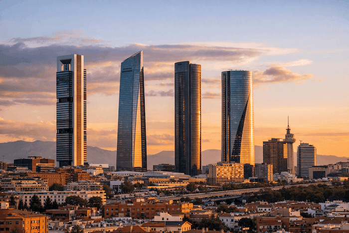 Vue panoramique du quartier financier de Madrid au coucher du soleil, avec les quatre tours modernes dominant la skyline, symbole du dynamisme économique espagnol.