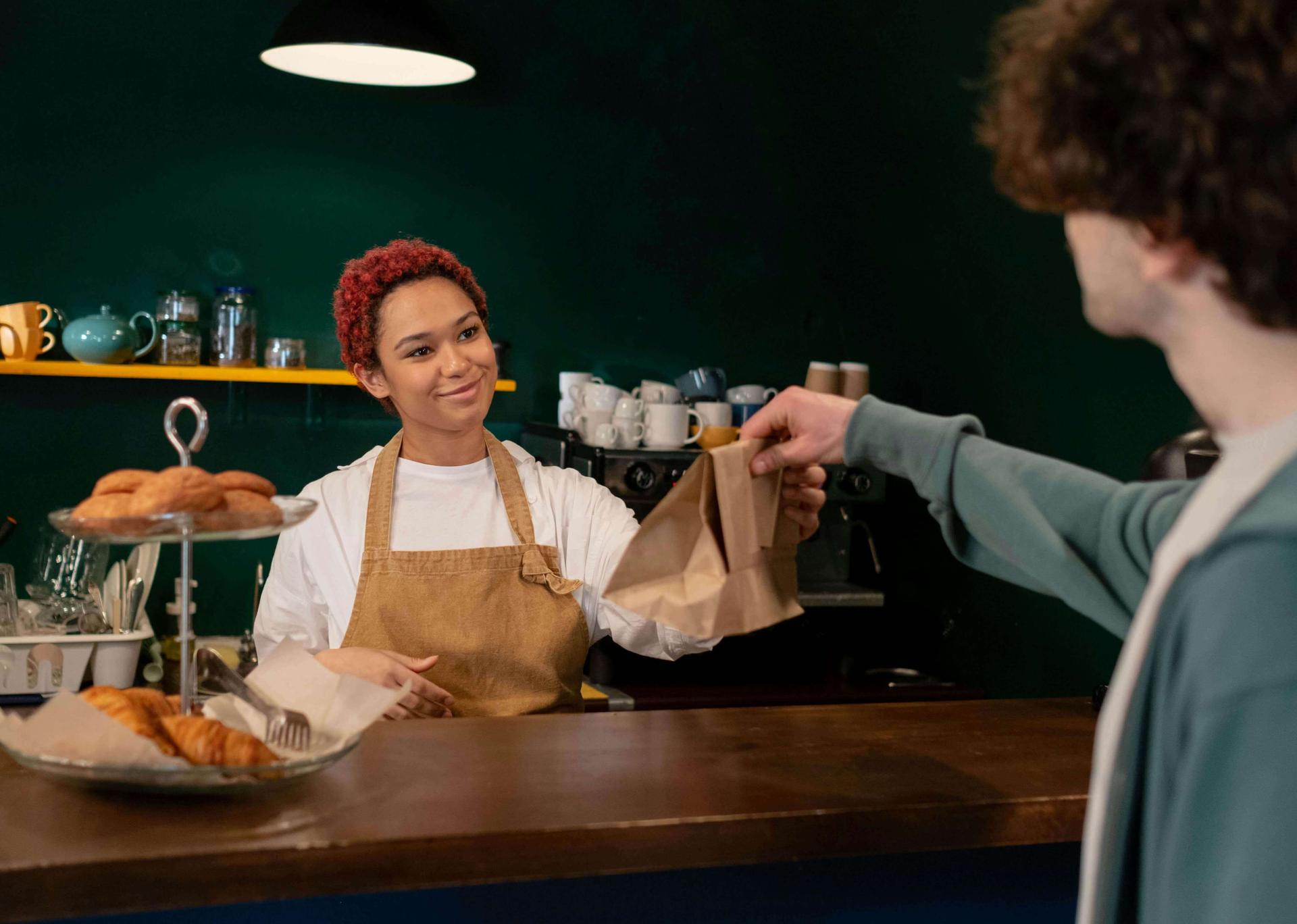 Une dame dans un restaurant donne un doggy bag à un client