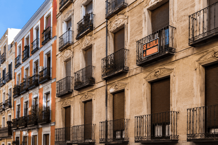 Façades d’immeubles résidentiels en Espagne avec plusieurs volets fermés et une pancarte “Se alquila”, illustration de la crise du logement et des logements vacants.