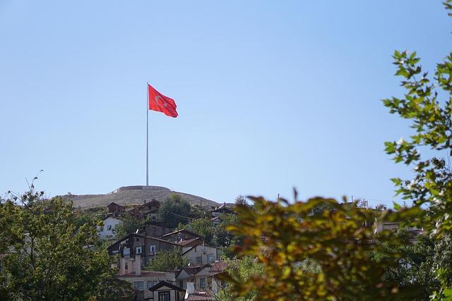 Un drapeau turc situé en haut d'une colline, un villlage s'étendant sur les pentes de celle-ci