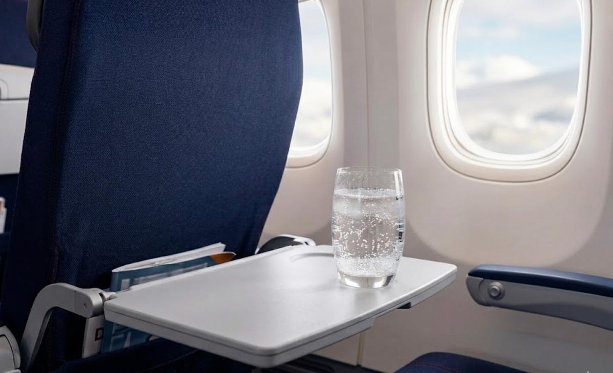 Un verre de boisson gazeuse sur une tablette dans un avion