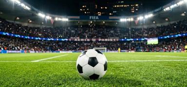 Un ballon de football sur un stade éclairé représentant les matchs FIFA 2026