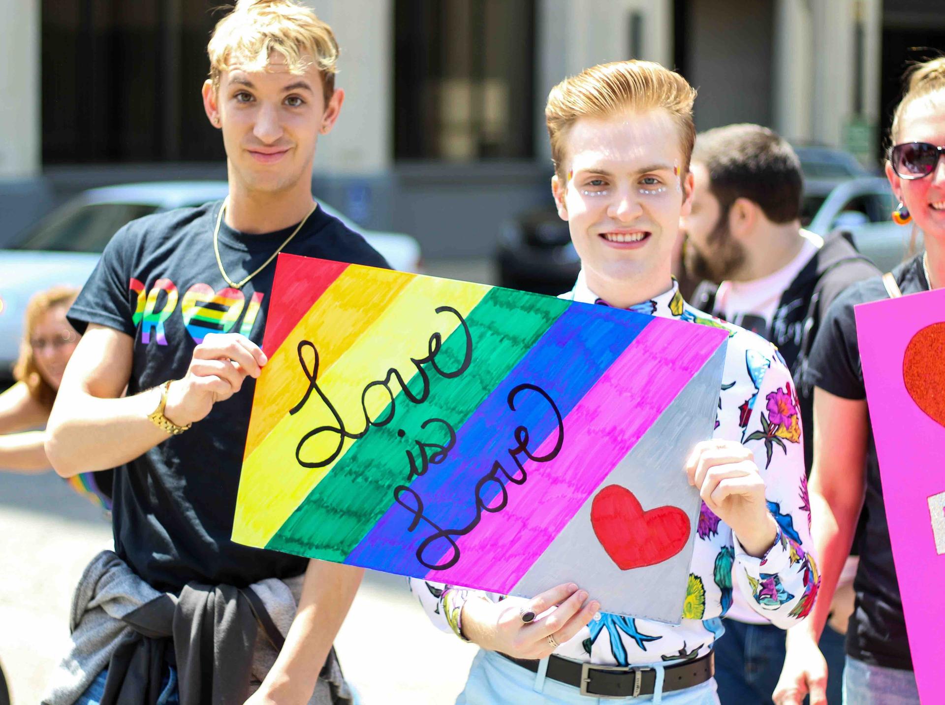 Deux personnes tenant un signe qui indique Love is Love