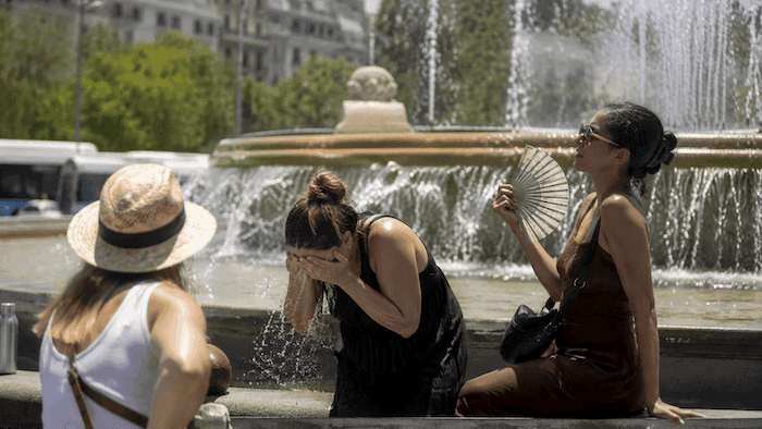 Des habitants se rafraîchissent autour d’une fontaine en pleine vague de chaleur, sous un soleil de plomb, dans une ville espagnole au début de l’été 2026.