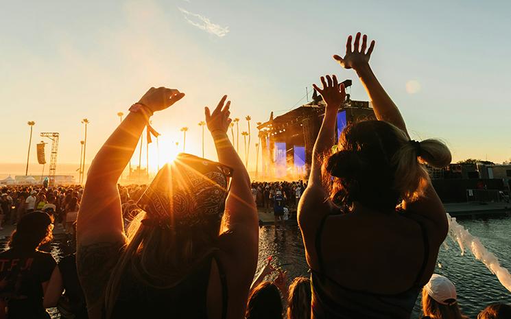 Deux filles dansant devant une scène musicale pendant un coucher de soleil