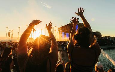 Deux filles dansant devant une scène musicale pendant un coucher de soleil
