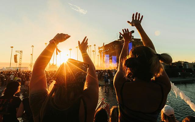 Deux filles dansant devant une scène musicale pendant un coucher de soleil