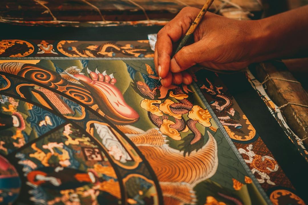 la main d'un artiste qui tient un pinceau fin et finalise une peinture traditionnelle balinaise