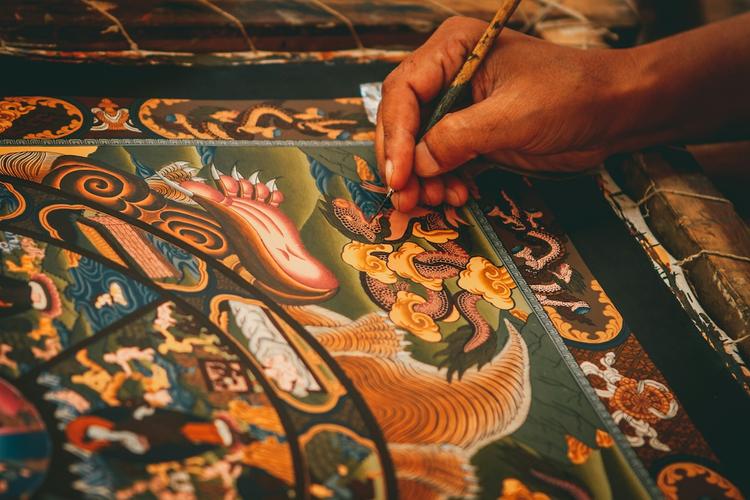 la main d'un artiste qui tient un pinceau fin et finalise une peinture traditionnelle balinaise