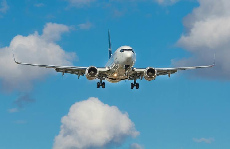 un avion en vol de face avec quelques nuages sur un ciel bleu