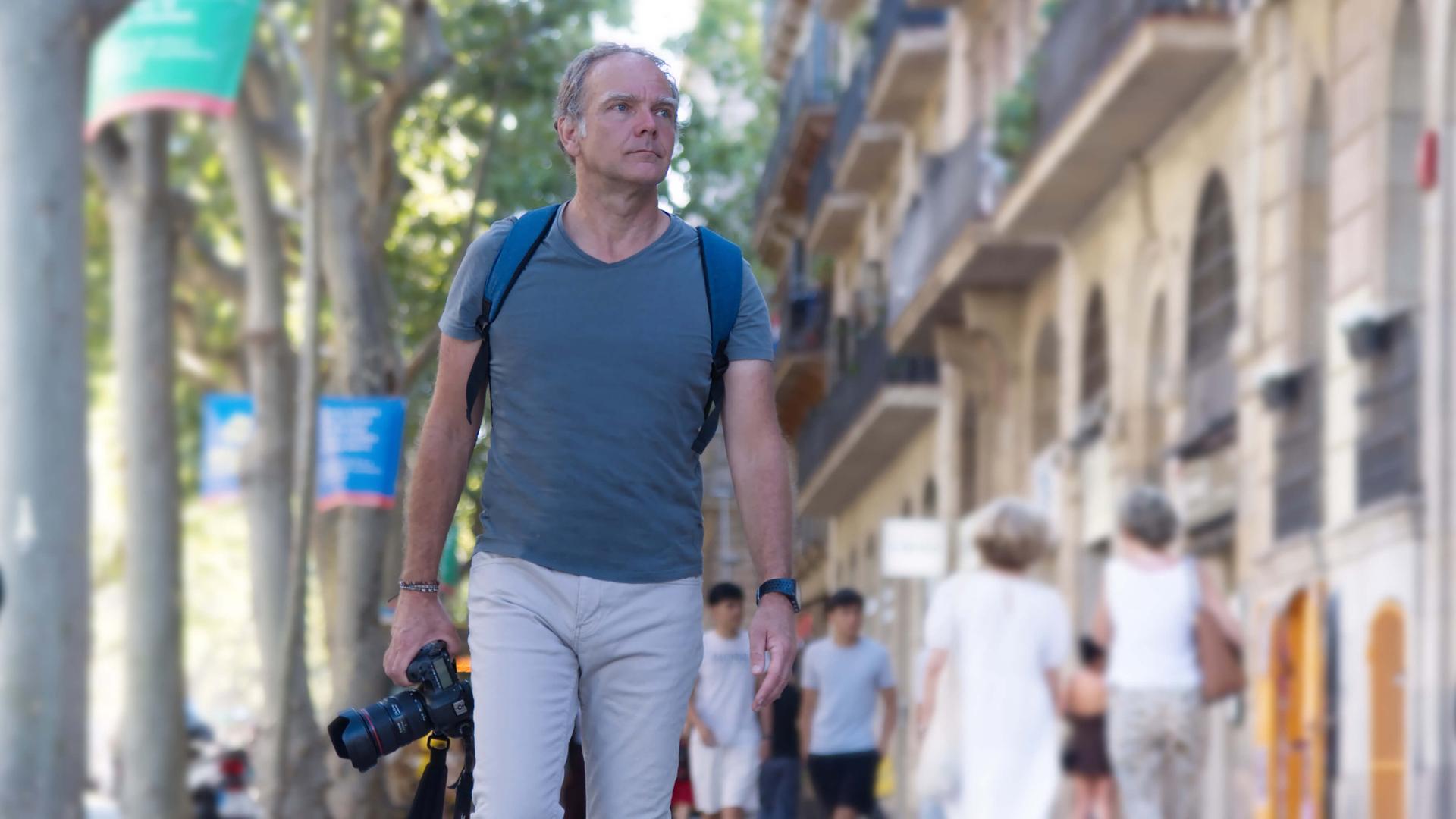 Photo de Bernard Tartinville dans une rue avec son appareil photo à la main