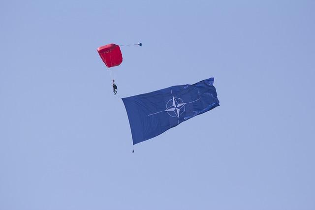 Zoom sur un parachutiste traînant dans son sillage le drapeau de l'OTAN
