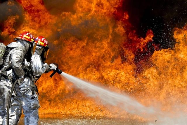 Des pompiers courageux en action éteignant un grand incendie avec détermination et travail d'équipe.