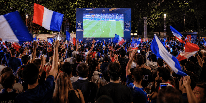 Des supporters français réunis devant un écran géant en plein air pour suivre la demi-finale France - Espagne de la Coupe du Monde dans une ambiance festive.