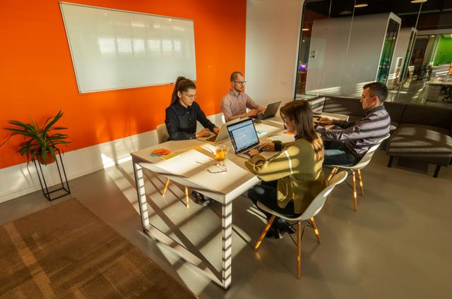 Un groupe de personnes avec des ordinateurs assises autour d'une table.