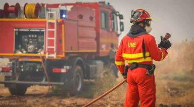 un pompier de la Unidad Militar de Emergencias avec un tuyau devant un camion pour éteindre un incendie en espagne