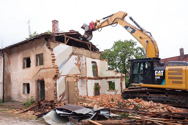 Vue d'un chantier de démolition, le bâtiment se trouvant à gauche et une pelleteuse à droite