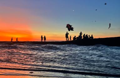 une plage de bali au coucher du soleil avec des cerf volants au loin