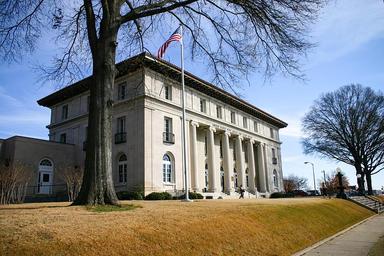 Vue de profil d'un bâtiment public de style néoclassique, le drapeau américain étant monté sur un mât à gauche de l'image
