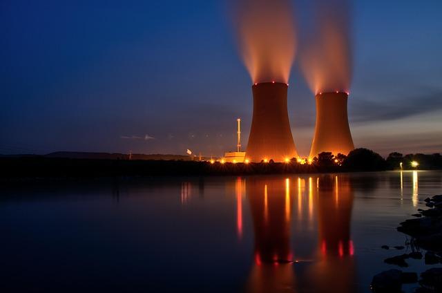 Vue de deux tours de refroidissement nucléaire au crépuscule, de l'autre côté d'un fleuve
